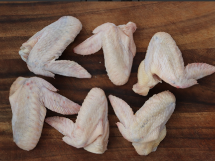 Raw Sommerlad heritage chicken wings arranged on a wooden board, six intact pieces.